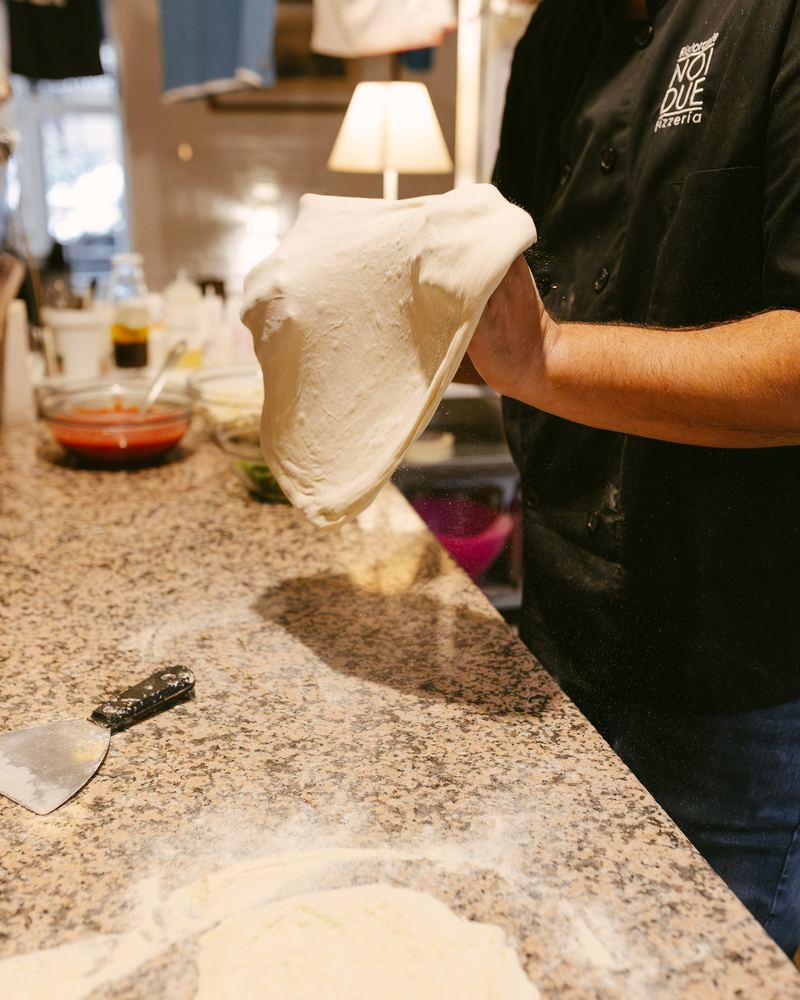 El pizzaiolo estira la masa a mano sobre la encimera