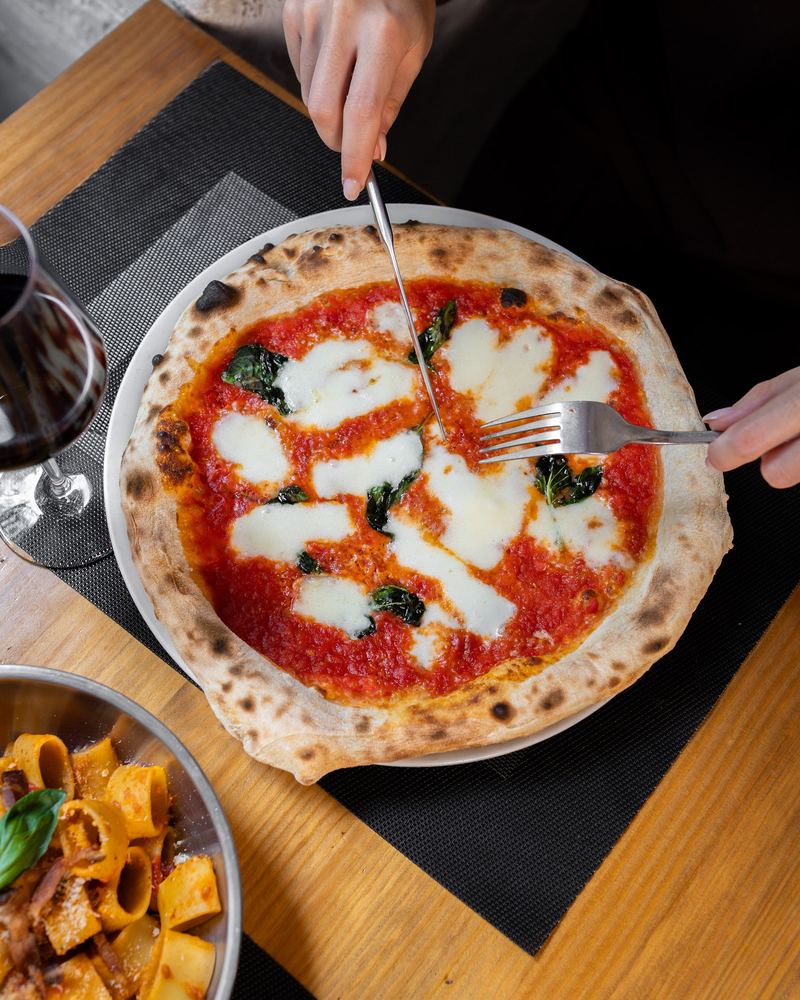 Margherita cortada en la mesa, junto a una copa de vino tinto