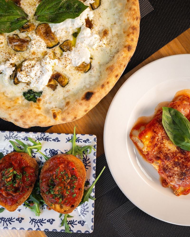 Pizza, antipasti y pasta servidos juntos en la mesa
